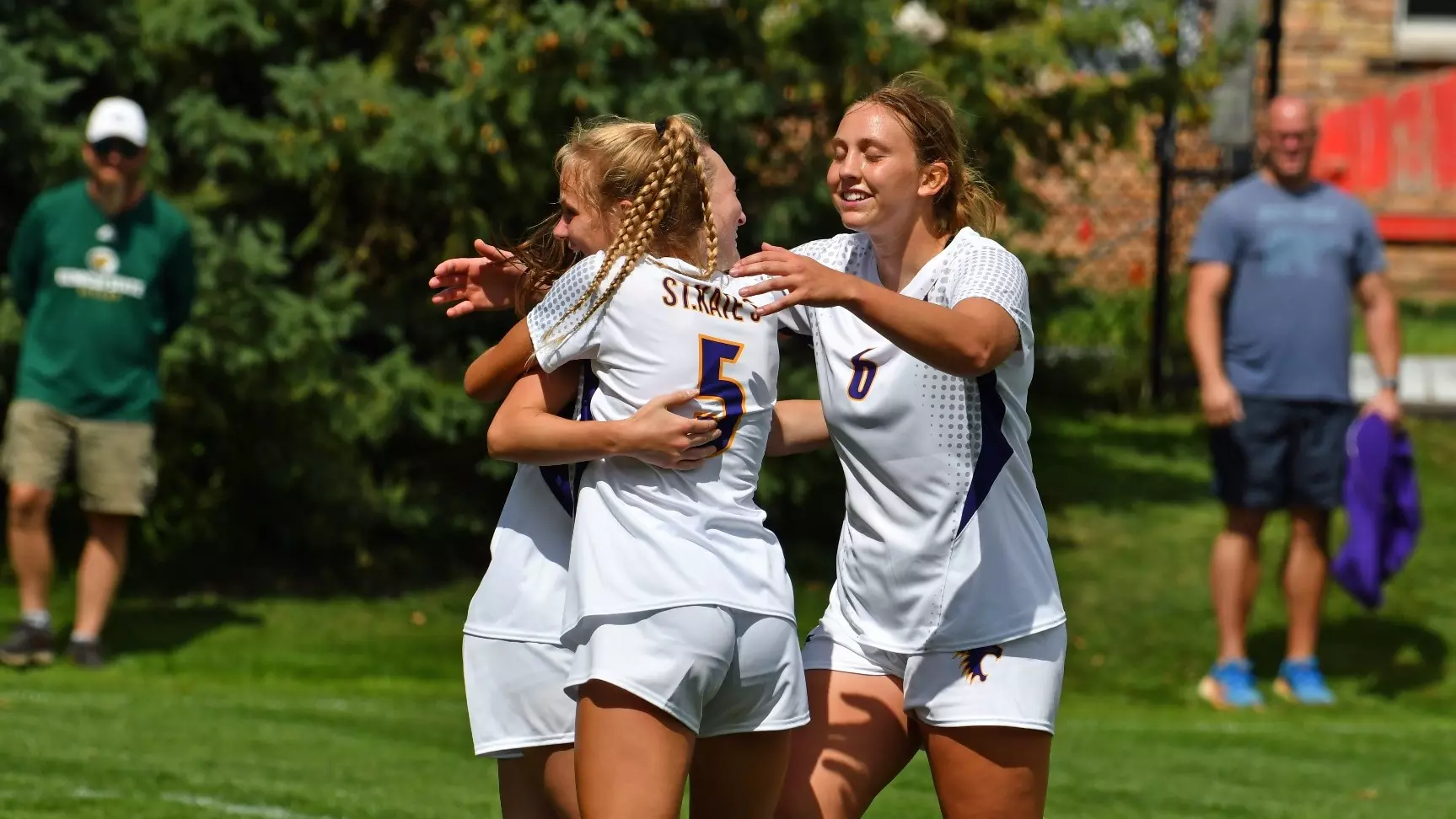 amanda elton, ari green and briana henaman hugging on the soccer field