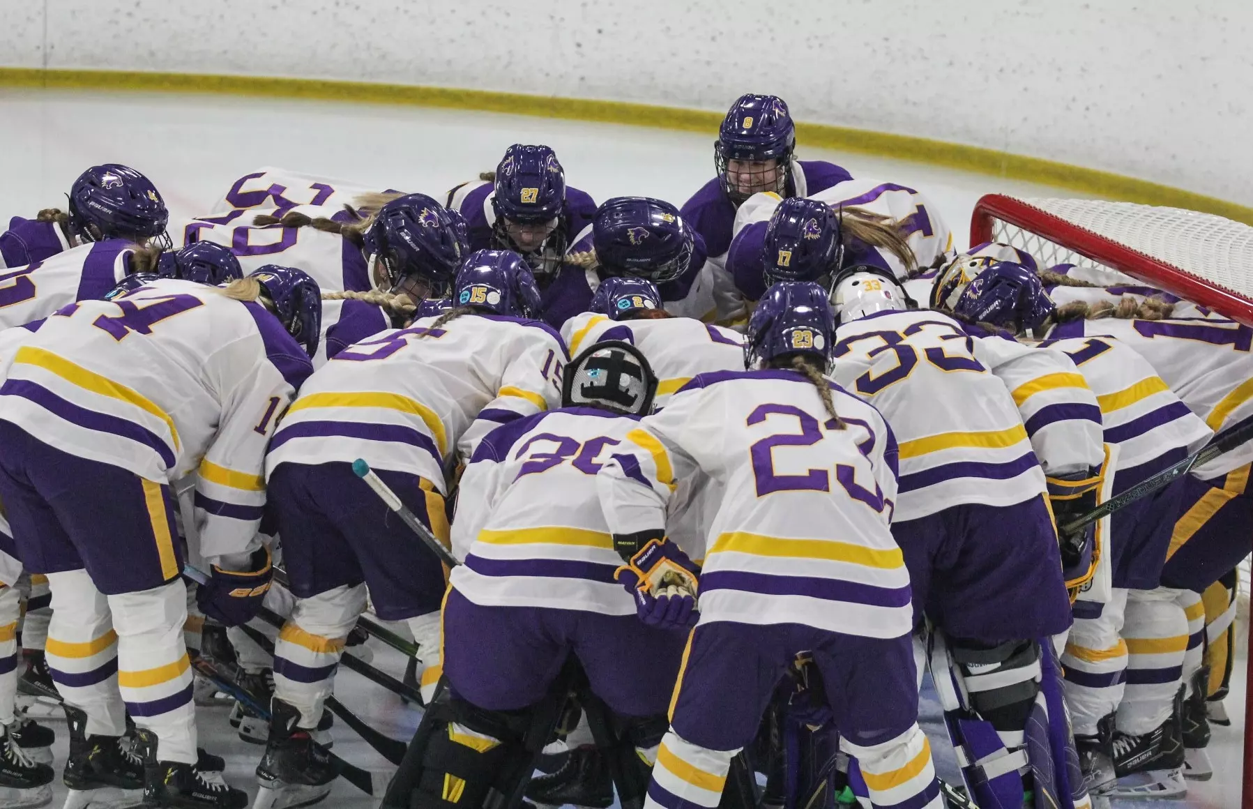 hockey team huddle around the net